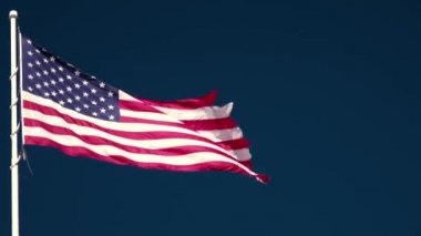 Mavi gökyüzüne ve beyaz bulutlara karşı dalgalanan Amerikan bayrağı. 