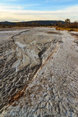 Amerika 'nın New Mexico çölünde kurumuş bir nehir yatağında yüzeyde kırmızı kil ve beyaz tuz kırılması.