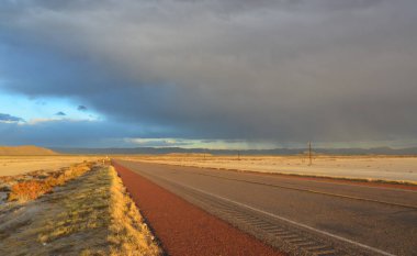 Kırmızı günbatımında yollar ve New Mexico 'daki Guadalupe Dağları' nın arka planında gök gürültülü bulutlar.