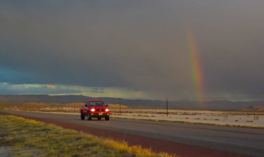 NEW MEXICO, ABD - 22 Kasım 2019: New Mexico 'daki Guadalupe Dağları' nın arka planında, kırmızı günbatımında ve gök gürültülü bulutlarda yol alan araba