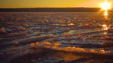 Donmuş suyun üzerinde kızıl gün batımı, kar ve buz desenleri. Tiligul haliçleri, Ukrayna