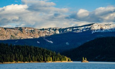 Karda dağlar, odunla kaplanmış. Dağların üzerinde kalın bulutlar. Montana, ABD