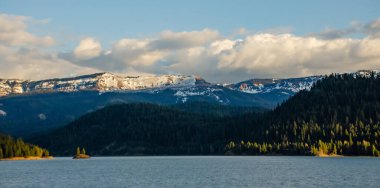 Karda dağlar, odunla kaplanmış. Dağların üzerinde kalın bulutlar. Montana, ABD