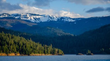 Karda dağlar, odunla kaplanmış. Dağların üzerinde kalın bulutlar. Montana, ABD