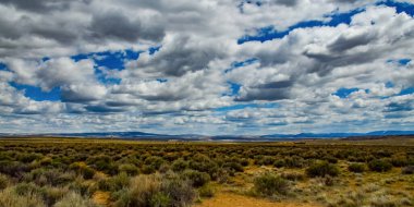 Rüzgâr türbinleri büyük beyaz bulutların arka planında, Utah, ABD 'deki araba penceresinden esiyor.
