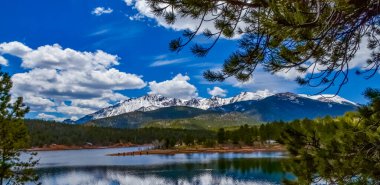 Pike Peak Panorama 'da. Colorado Baharı, Colorado, ABD 'deki Pikes Tepesi Dağları' nda bir dağ gölü yakınında karla kaplı ve ormanlı dağlar.