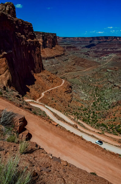 Dirt road at the bottom of the canyon among the layered geological formations of red rocks. USA