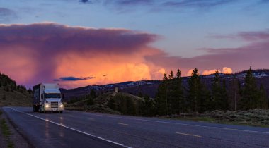 Dağların üzerinde güzel kırmızı gün batımı, yolda araba. ABD