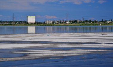 Büyük beyaz bir bina, Ukrayna 'daki Kuyalnitsky haliçinin tuzlu suyuna, siyah çamur ve sudan oluşan bir araziye yansıyor.