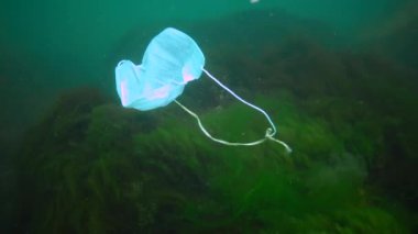 Suyun altındaki plastik. Covid-19 salgınından sonra okyanusta yüzen bir tıbbi maske. Çevre kirliliği. İnsanlar Salgın Karantina Sonrası Tıbbi Maske Atmışlar.