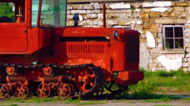 Old red tractor on the background of a destroyed building, Ukraine