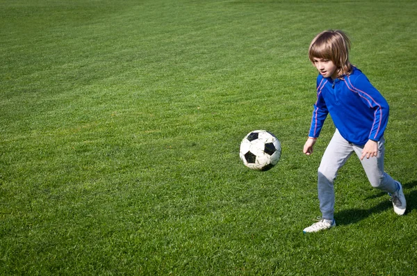 Menino jogando futebol no parque - Ação autêntica com bola de futebol - copiar o espaço direito e esquerdo - formato de paisagem — Fotografia de Stock