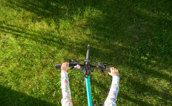 Genç kız parlak yeşil çimlerde bisiklet sürüyor. — Stok fotoğraf