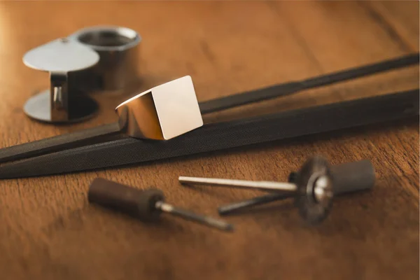 Empty signet ring and jeweler tools on wooden antique table