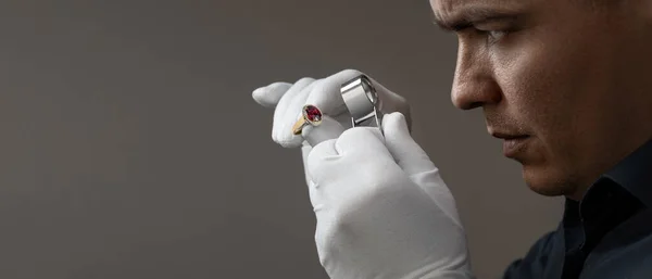 Joyero masculino examinando anillo de rubí dorado en taller Imagen De Stock
