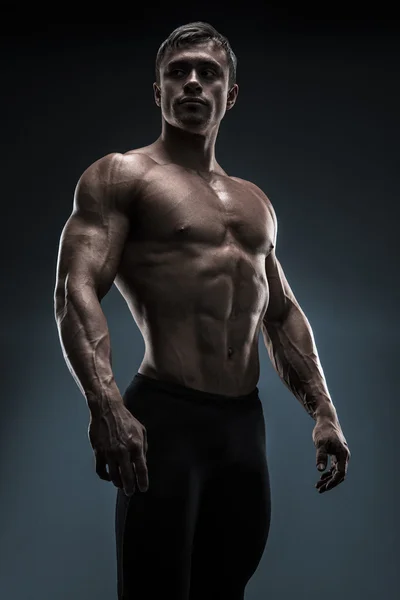 Handsome muscular bodybuilder posing over black background — Stock Photo, Image