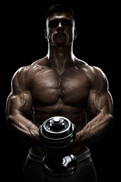 Silhouette of a bodybuilder pumping up muscles with dumbbell — Stock Photo, Image