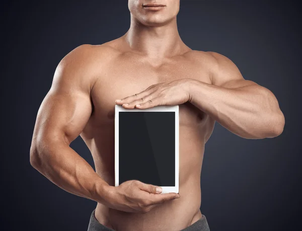 Фитнес-мужчина держит вертикально цифровой планшет с чистым экраном — стоковое фото