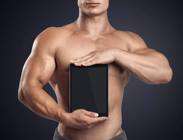 Fitness masculino sosteniendo verticalmente tableta digital con pantalla en blanco —  Fotos de Stock