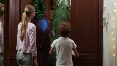 Noel için Bayram Ağacı Teslimatı. Bir kurye eve büyük ambalajlı bir Noel ağacı getirir. O, çocuklar tarafından karşılanır. Kız tabletin üzerine imza atıyor. Kurye çocuğa Noel ağacı süsü verir.