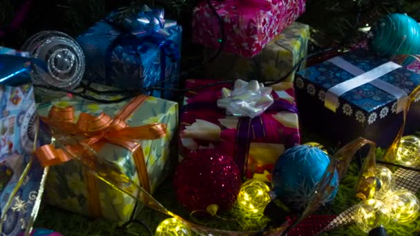 きらびやかな 休日の装飾や贈り物 カメラは 輝く弓 クリスマスツリーの装飾や輝くガーランドで飾られたさまざまなギフトボックスに沿ってゆっくりと移動します — ストック動画