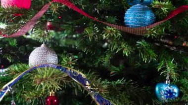 Parlak Noel anıları. Parlak parlak çelenklerle süslenmiş Noel ağacı dalları ve Noel süslemeleri kameranın önünde yavaşça hareket ediyor