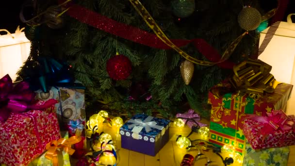 クリスマスツリーの下のギフトを見つけた カメラはギフトがあるクリスマスツリーの底にゆっくり動く 手を徐々に両側にギフトボックスを拾う — ストック動画