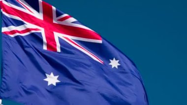 Yeni Zelanda Bayrağı Rüzgarı Kıpırdatıyor. Büyük Eyalet Bayrağı güneş tarafından aydınlatılır ve mavi gökyüzüne karşı destansı bir şekilde dalgalanır. Slow Motion 240 fps