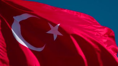 Güneşin Türk Bayrağı Işığı. Büyük Eyalet Bayrağı güneş tarafından aydınlatılır ve mavi gökyüzüne karşı destansı bir şekilde dalgalanır. Slow Motion 240 fps