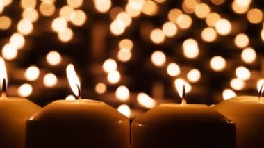 Dramatik Mum Sahnesi. Dört büyük mum arka planda birçok küçük ışığa karşı kapanır. Hava yavaşça sallanan ateş. 120fps hızla çekilmiştir.