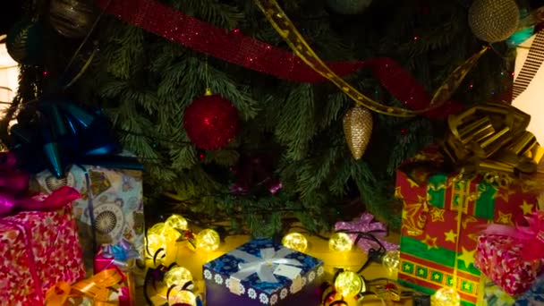 クリスマスは家族全員にとって驚きです カメラはゆっくりとカラフルな箱の中に贈り物がある装飾されたクリスマスツリーの下に降りて行きます — ストック動画