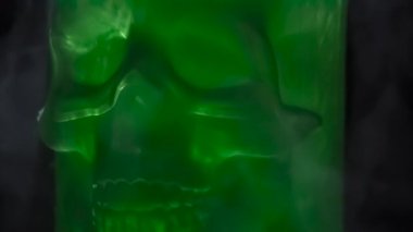 Matte Green Skull. Buzlu yeşil cam kafatası, siyah arkaplana karşı yavaş yavaş buz buharında döner.