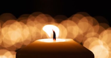 Dramatic Fluttering Candle Flame. A large candle close up against the background of a set of blurry lights. Filmed at a speed of 120fps