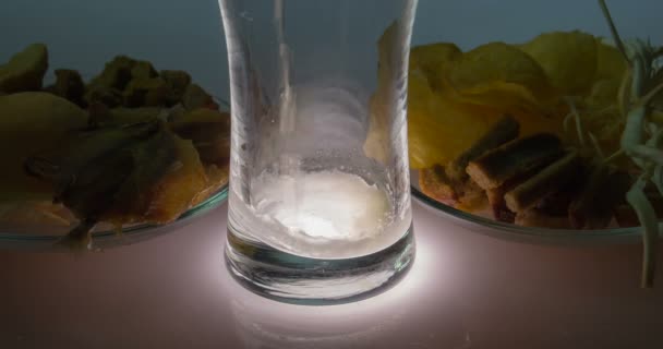 В стакан наливает пиво и соленые закуски — стоковое видео