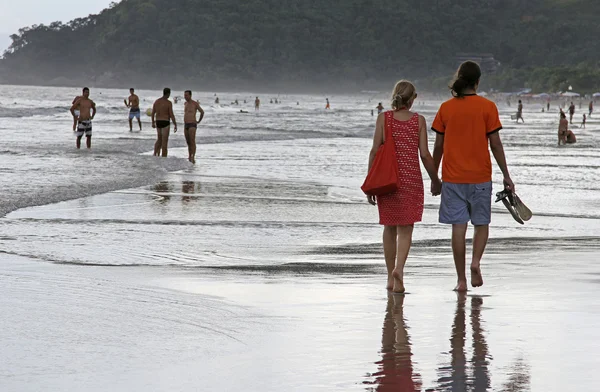 A couple walking along beach at sunset — Stock Photo, Image