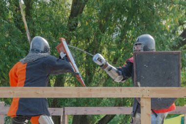 Orta Çağ zırhlı 60 santimlik savaşçılar arenada savaşıyor. Kılıçlarla donatılmış. Demir miğferler ve kalkanlar tarafından korunuyorlar. Ortaçağ Avrupa şövalye turnuvalarının tarihi yeniden yapılandırması