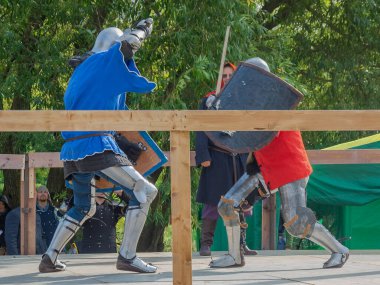 Tver / Rusya - 29 Eylül 2020: Ağır zırhlı savaşçılar kılıçlarla savaşıyor. Arka planda, hakem ve seyirciler. Ortaçağ Avrupa şövalye turnuvalarının tarihi yeniden yapılandırması