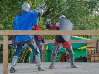 Tver / Rusya - 29 Eylül 2020: Ağır zırhlı savaşçılar kılıçlarla savaşıyor. Arka planda, hakem ve seyirciler. Ortaçağ Avrupa şövalye turnuvalarının tarihi yeniden yapılandırması