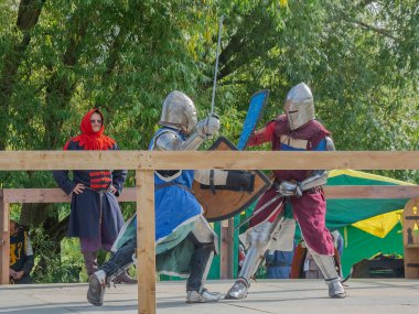 Tver / Rusya - 29 Eylül 2020: Ağır zırhlı savaşçılar kılıçlarla savaşıyor. Arka planda, hakem ve seyirciler. Ortaçağ Avrupa şövalye turnuvalarının tarihi yeniden yapılandırması