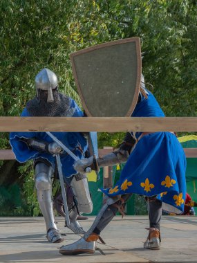 Orta Çağ zırhlı 60 santimlik savaşçılar arenada savaşıyor. Kılıçlarla donatılmış. Demir miğferler ve kalkanlar tarafından korunuyorlar. Ortaçağ Avrupa şövalye turnuvalarının tarihi yeniden yapılandırması