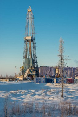 Kuzey tarlasında petrol ve gaz kuyuları kazıyor. Kutup dondurucu soğuk günü. Bir sondaj teçhizatıyla karda kış ormanı-tundra manzarası. Güzel gökyüzü