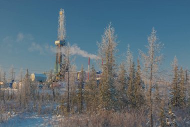 Kuzey tarlasında petrol ve gaz kuyuları kazıyor. Kutup dondurucu soğuk günü. Bir sondaj teçhizatıyla karda kış ormanı-tundra manzarası. Güzel gökyüzü