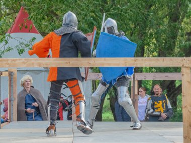 Tver / Rusya - 29 Eylül 2020: Ağır zırhlı savaşçılar kılıçlarla savaşıyor. Arka planda, hakem ve seyirciler. Ortaçağ Avrupa şövalye turnuvalarının tarihi yeniden yapılandırması