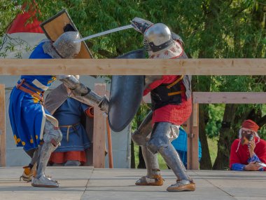 Tver / Rusya - 29 Eylül 2020: Ağır zırhlı savaşçılar kılıçlarla savaşıyor. Arka planda, hakem ve seyirciler. Ortaçağ Avrupa şövalye turnuvalarının tarihi yeniden yapılandırması