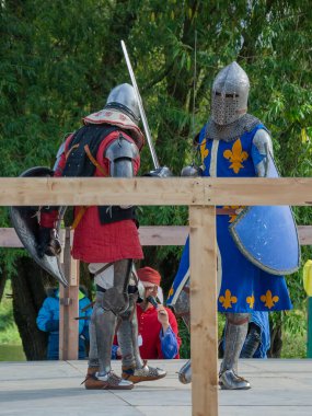 Tver / Rusya - 29 Eylül 2020: Ağır zırhlı savaşçılar kılıçlarla savaşıyor. Arka planda, hakem ve seyirciler. Ortaçağ Avrupa şövalye turnuvalarının tarihi yeniden yapılandırması