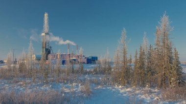 Kuzey tarlasında petrol ve gaz kuyuları kazıyor. Kutup dondurucu soğuk günü. Bir sondaj teçhizatıyla karda kış ormanı-tundra manzarası. Güzel gökyüzü