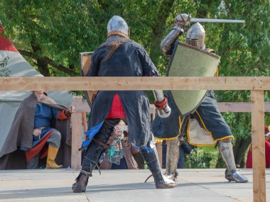 Tver / Rusya - 29 Eylül 2020: Ağır zırhlı savaşçılar kılıçlarla savaşıyor. Arka planda, hakem ve seyirciler. Ortaçağ Avrupa şövalye turnuvalarının tarihi yeniden yapılandırması