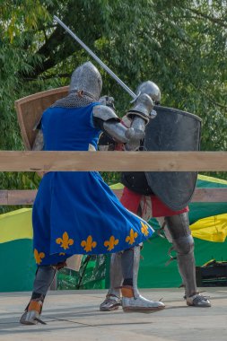 Orta Çağ zırhlı 60 santimlik savaşçılar arenada savaşıyor. Kılıçlarla donatılmış. Demir miğferler ve kalkanlar tarafından korunuyorlar. Ortaçağ Avrupa şövalye turnuvalarının tarihi yeniden yapılandırması