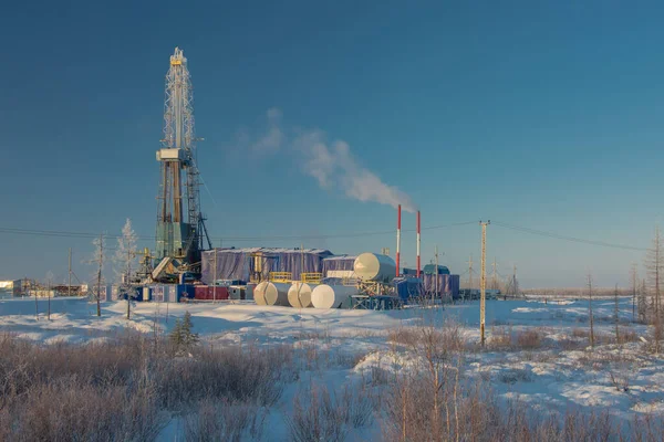 Drilling oil and gas wells in the northern field. Polar frosty day. Winter forest-tundra landscape in the snow with a drilling rig. Beautiful sky