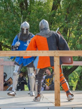 Tver / Rusya - 29 Eylül 2020: Ağır zırhlı savaşçılar kılıçlarla savaşıyor. Arka planda, hakem ve seyirciler. Ortaçağ Avrupa şövalye turnuvalarının tarihi yeniden yapılandırması